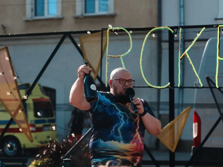 Maciej Gomułka z mikrofonem na scenie plenerowej